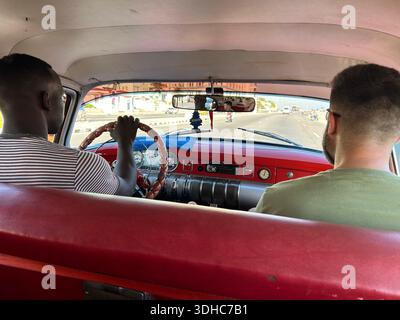 Blick aus dem Inneren eines fahrenden Autos mit Fahrer und Beifahrer auf der Vorderseite, Kuba Stockfoto