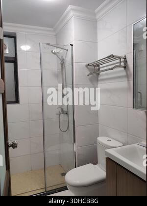 Modernes Bad mit Glasdusche und weiß gefliesten Wänden Stockfoto