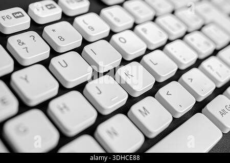 Eine weiße Computertastatur mit schwarzem Schriftzug auf dunkler Oberfläche. Stockfoto