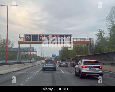 Wien, Österreich: 13.04.2025 befahrene Stadtautobahn mit Fahrzeugen mit digitalen Geschwindigkeitsbegrenzungsschildern, die moderne Verkehrsmittel, Pendelverkehr und Straßensicherheit anzeigen. Stockfoto