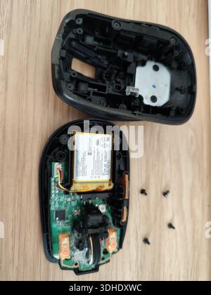 Zerlegte Computermaus mit internen Komponenten und Schrauben auf Holzoberfläche Stockfoto