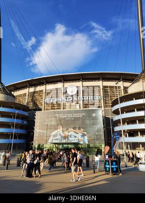 Außenansicht des Etihad Stadions mit Fans, die unter blauem Himmel draußen laufen Stockfoto