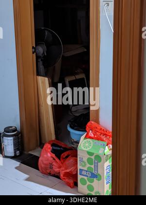 Überfüllter Eingang mit Haushaltsgegenständen und Aufbewahrungsboxen in einem Wohnraum Stockfoto