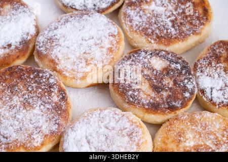 Goldener Hüttenkäsepfannkuchen, Staubzucker. Warmer Hausstil auf Leinenserviette mit gebräunten Kanten und weichen Mittelpunkten, Puderzucker-Funkeln, Marmelade und Stockfoto