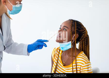 Schwarze Patientin, die auf einen Arzt schaut, der PCR-Test macht Stockfoto