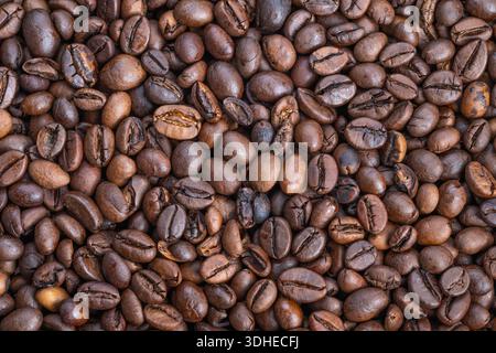 Geröstete Kaffeebohnen aus der Nähe, Barista-Charge bereit zum Mahlen, warme Brauntöne, glänzende Öle und eine haptische Oberfläche erinnern an den Morgen des Kaffees Stockfoto