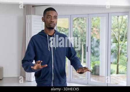 Afroamerikanischer Mann, der im Wohnzimmer durch Glastüren die Hände balanciert Stockfoto
