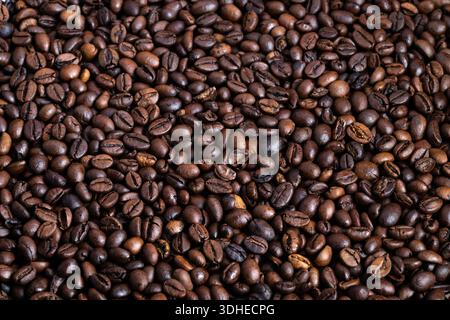 Das strukturierte Muster gerösteter Kaffeebohnen im Hintergrund, die geringe Schärfentiefe und der kräftige braune Farbverlauf bilden einen vielseitigen Hintergrund für die Darstellung von Speisen und Getränken Stockfoto
