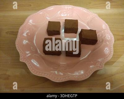 Schokoladen-Brownies serviert auf einem rosa Keramikteller Stockfoto