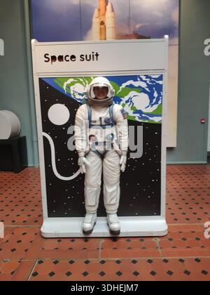 Astronauten-Raumanzug in voller Größe im Museum mit Erde- und Mondkulisse Stockfoto