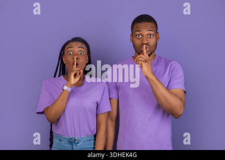 Schwarzes Paar, das Finger auf die Lippen stampft und ein Zeichen für die Stille macht Stockfoto