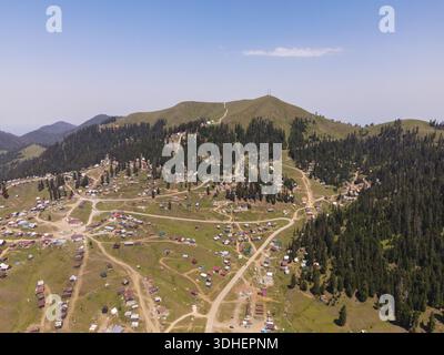 Aus der Vogelperspektive auf ein Hochland-Dorf im Kleinen Kaukasus in Georgien bei Bakhmaro zeigt Hütten, Bauernhäuser, unbefestigte Straßen, Weiden und Funkmasten unter dem Kleinen Stockfoto