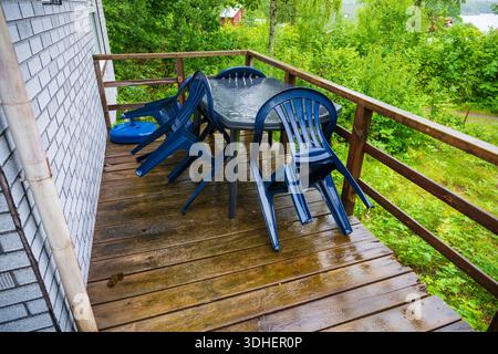 Regengetränkte Terrasse mit gestapelten Plastikstühlen Stockfoto