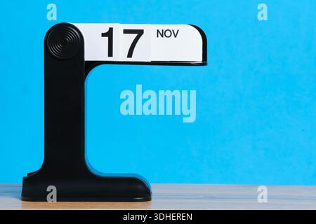 Moderner Flipkalender mit dem 17. November auf einem Holztisch mit hellblauem Hintergrund Stockfoto