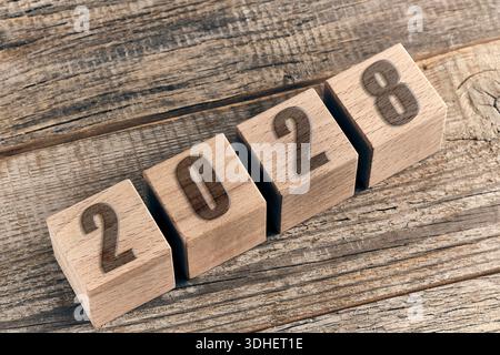 2028 Neujahrsschild aus Holzwürfeln auf einem rustikalen Holztisch. Draufsicht, Kopierraum Stockfoto