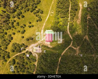 Die Anlage auf dem Berggipfel im georgischen Kaukasus hat ein rot-grünes Dach, Schotterpisten und Skiliftmasten. Warmes Mittagslicht wirft lange Schatten Stockfoto