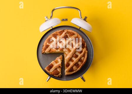 Süßer amerikanischer Kuchen mit Äpfeln, Birnen und Zimt, ein hausgemachtes Dessert. Apple American Pie als Plattenkonzept anstelle eines Zifferblatts bei einem Vintage Alarm cl Stockfoto