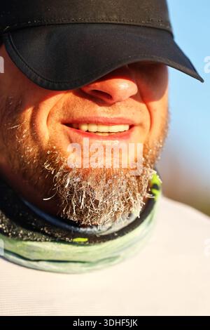 Mann mit Frostbart, der in der kalten Wintersonne lächelt Stockfoto