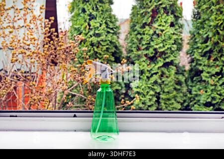 Sprühen Sie die Flasche mit Wasser auf die Fensterbank in der Nähe eines offenen Fensters Stockfoto