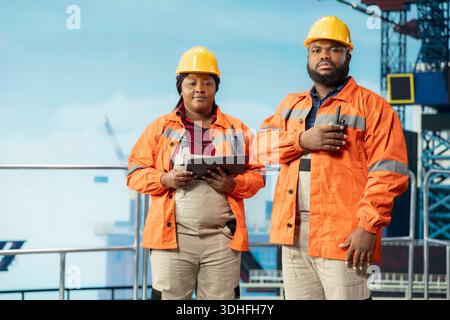 Porträt von Offshore-Plattformarbeitern, die Derrick-Managementsysteme für eine effizientere Ölförderung konfigurieren. Mitarbeiter von afroamerikanischen Bohrgeräten, die Meeresbodenanalysen mit einem Tablet durchführen Stockfoto