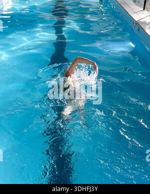 Der Schwimmer trainiert im klaren Wasser des Hallenbades, während er Streicheleinheiten übt. Stockfoto