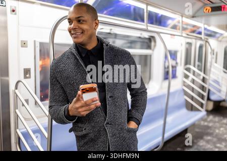 Junger Geschäftsmann Pendler mit Smartphone in der New yorker U-Bahn Stockfoto