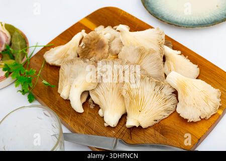 Es gibt einen Haufen roher Austernpilze auf dem Schneidebrett. Stockfoto