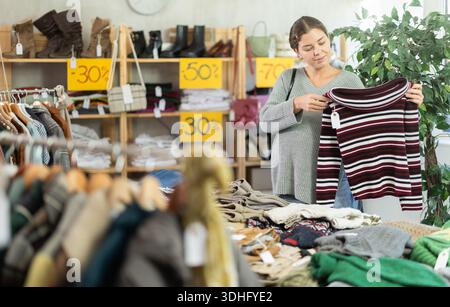 Schwangere Frau, die einen Pullover in einem Bekleidungsgeschäft wählt Stockfoto