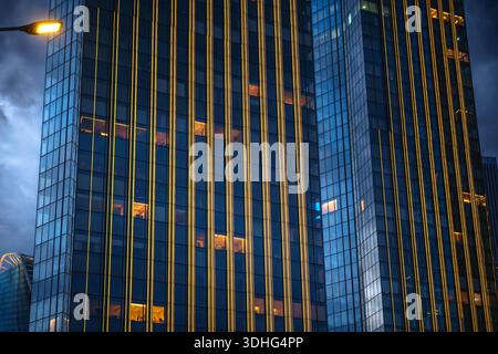 Glasfassade eines modernen Moskauer Stadtturms im Abendlicht. Sturmwolken, beleuchtete Fenster, vertikale Linien. Aufgenommen mit Sony A7 IV, hohe Auflösung. H Stockfoto