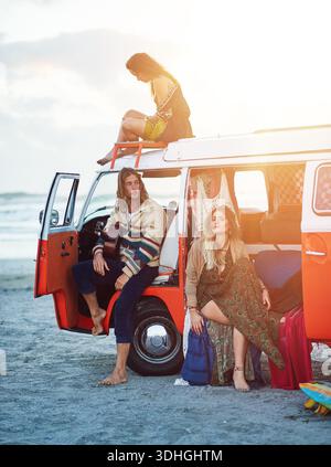 Menschen, Freunde und entspannen Sie sich mit einem Caravan am Strand für Roadtrip-Abenteuer oder Outdoor-Reise zusammen. Hipster, Gruppe oder Reisende mit Fahrzeug für Stockfoto