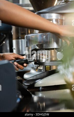 Espresso-Portafilter, der in den Gruppenkopf auf reflektierendem Kaffeekocher einrastet, warme Metallelemente Stockfoto