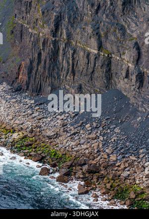Talus- und Felsstrand am Fuße der Cliffs of Moher, wo Atlantische Wellen Algen-bedeckte Felsen unter einer Klippe, Co. Clare, Irland. Stockfoto