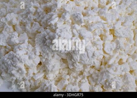 Cremige Hüttenkäseklumpen zum Frühstück, proteinreiche Zutat, löffelbereite Quark, helle natürliche Beleuchtung, gesundes Esskonzept, Salat und glatt Stockfoto