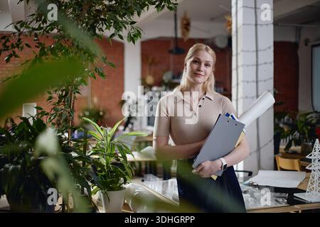 Porträt der jungen Erwachsenen Kaukasierin, die Dokumente im modernen Büro hält Stockfoto
