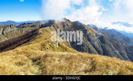 Eine Weitwinkellandschaft, aufgenommen vom felsigen Gipfel des Monte Brusa, die die sanften Grate des italienischen Apennins unter einem hellblauen Himmel zeigt. Stockfoto