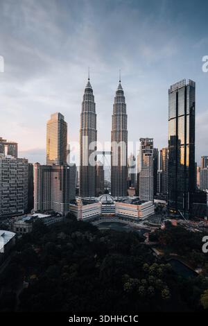 Blick aus der Vogelperspektive auf die berühmten Petronas Twin Towers, die die Skyline inmitten eines Wandteppichs aus modernen Wolkenkratzern und üppigem Grün durchdringen, Kuala Lumpur, Malaysia. Stockfoto