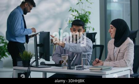 Drei Geschäftskollegen. Geschäftsmann mit islamischer Geschäftsfrau diskutieren über reden, arbeiten, Computer aussehend, Arabisch-Mann-Chef kommt ins Amt Stockfoto