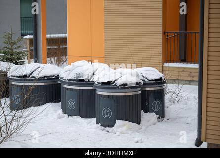 Moderne Abfallrecyclingbehälter in Winterwohngebieten mit Schnee- und Öko-Symbolen Stockfoto