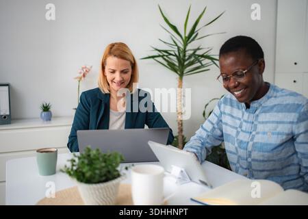 Verschiedene Kollegen arbeiten mit Laptop und Tablet zusammen Stockfoto
