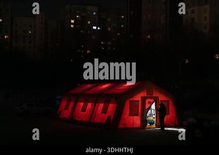 Krieg in der Ukraine. Ein beleuchtetes Point of Invincibility-Zelt steht in einem dunklen Kiewer Innenhof während eines Stromausfalls. Die Bewohner suchen Wärme und Elektrizität im mobilen Unterschlupf. Stockfoto