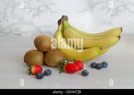 Zutaten für Banana Kiwi Smoothie: Bananen, Kiwi, Heidelbeeren und Erdbeeren. Helles Obst zum Entgiftungsfrühstück. Konzept von Frühstückskorb oder Würfel Stockfoto