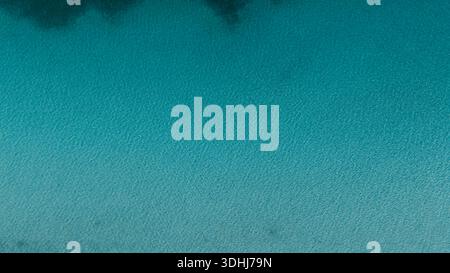 Luftaufnahme, die die Textur des tiefblauen und klaren Salda-Sees zeigt. Minimalistischer und friedlicher Hintergrund mit leichten Wellen auf der Wasseroberfläche. Stockfoto