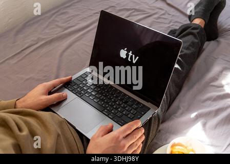 Bar, Montenegro, 22. Januar 2026, Mann, der auf der Website der Apple TV-Plattform einen Film auf einem Laptop ansieht, während er zu Hause auf dem Bett sitzt Stockfoto