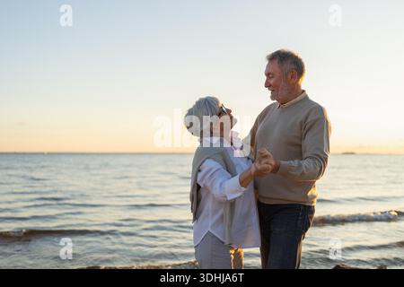 Bleiben Sie in Bewegung. Romantisches älteres Ehepaar, das gemeinsam am Strand im Freien tanzt. Glückliche lächelnde Familie pensionierter Mann Frau Ehemann Frau, die Spaß hat, die Zeit zusammen zu genießen. Familienmoment Love Care || Model veröffentlicht Stockfoto