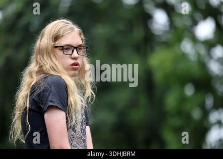 Nachdenkliche blonde Jugend mit einer Brille, die draußen seitlich schaut Stockfoto