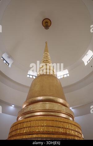 Eine Innenaufnahme einer hohen, goldfarbenen buddhistischen Stupa oder Pagode unter einer sauberen weißen runden Kuppel mit kleinen Fenstern. Stockfoto