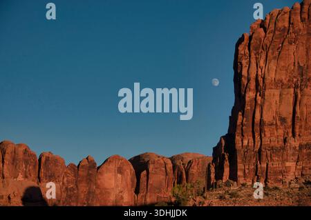 Foto des Mondes, der über den roten Klippen über dem Moonflower Canyon in der Nähe von Moab, Utah, aufsteigt. Stockfoto