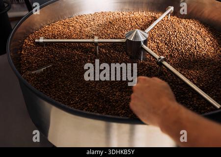 Die Kühltrommel einer industriellen Röstkaffeemaschine. Geröstete Bohnen kühlen nach dem Rösten im Fass ab. Die Kühltrommel von industriellem Röstguss Stockfoto