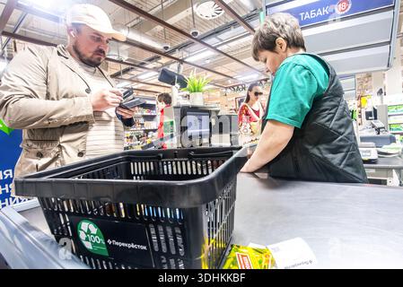 Samara, Russland - 1. Mai 2025: Ein Verkäufer bedient einen Kunden an der Kasse in einem Supermarkt in Perekrestok Stockfoto