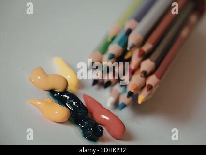 Eine Sammlung von leuchtenden Buntstiften, die neben einer Auswahl von gummiartigen Bonbons in verschiedenen hellen Farben liegen. Stockfoto